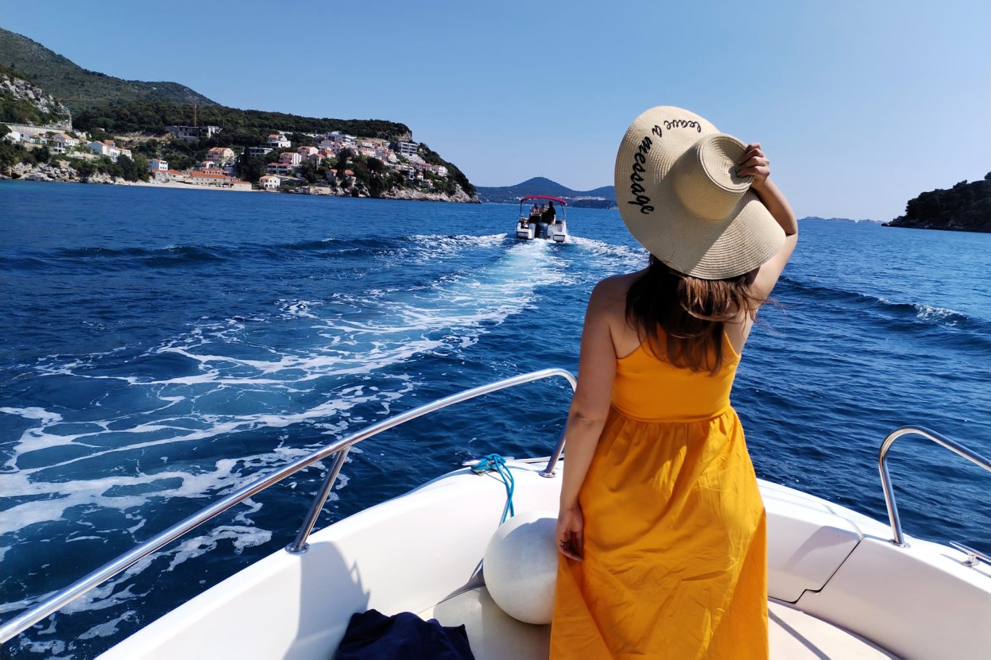 A girl with a summer hat on the bow of the boat